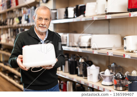 Mature man buyer examine toaster in detail before buying Mature man buyer examine toaster in detail before buying 136599407