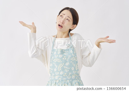 Woman wearing an apron making a gesture of giving up on a white background 136600654