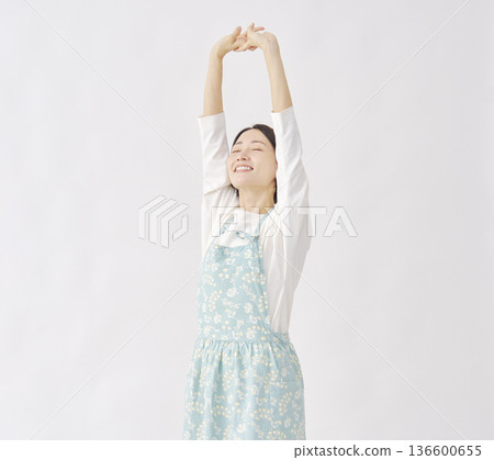 Woman wearing an apron stretching white background 136600655