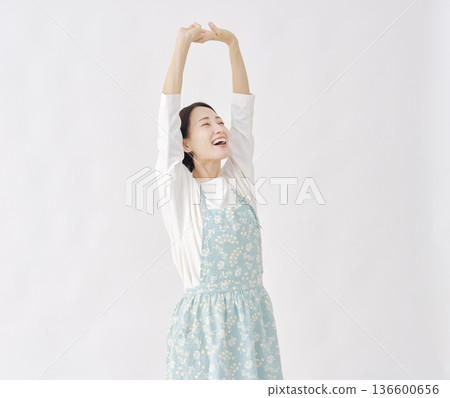 Woman wearing an apron stretching white background Woman wearing an apron stretching white background 136600656