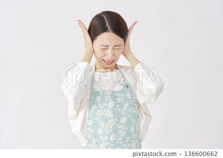 Woman wearing an apron covering her ears, white background Woman wearing an apron covering her ears, white background 136600662