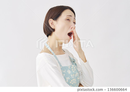 身穿圍裙的女子打哈欠，白色背景 136600664