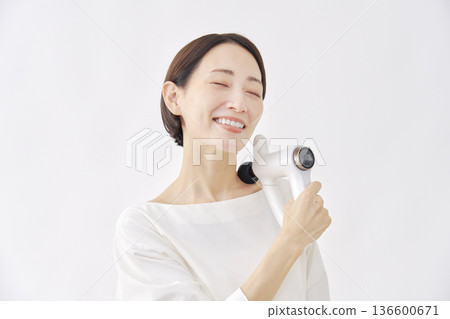 Woman using a massage gun, stiff shoulders, white background Woman using a massage gun, stiff shoulders, white background 136600671