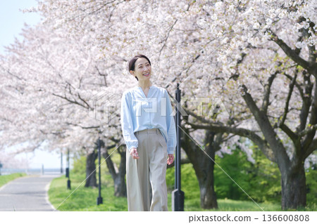 盛開的櫻花和一位女士在海濱長廊上散步 136600808