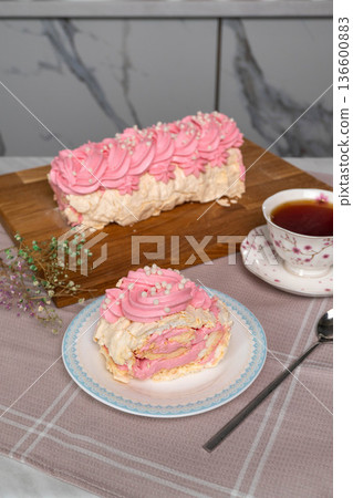 Pink cream meringue cake with cup of tea on table Pink cream meringue cake with cup of tea on table 136600883