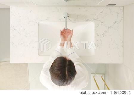 Aerial view of a woman washing her hands in a bathrobe Aerial view of a woman washing her hands in a bathrobe 136600965