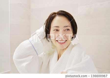 A woman wiping her wet hair with a bath towel after taking a bath 136600967