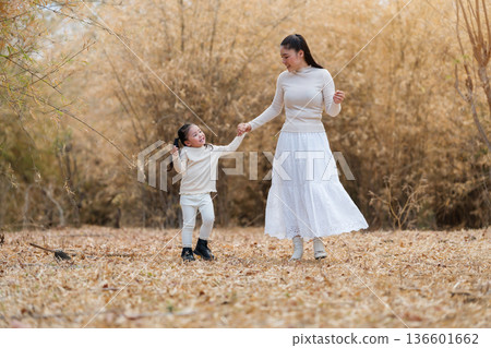 mother and child girl walking through a dry bamboo forest 136601662