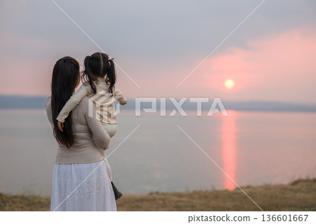 Loving mother holding child girl while watching the sunset glow 136601667
