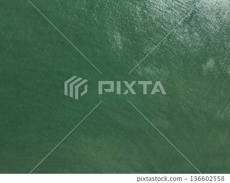 Clear water surface reflects light under bright conditions in ocean 136602558