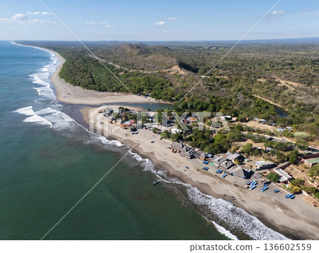 Coastal village near the beach with boats and trees in the distance 136602559