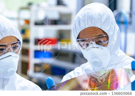 半導體工廠內身穿防護衣的男工人檢查矽片 136603068