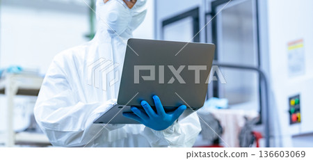 一名身穿防護服的男工人帶著筆記型電腦在工廠工作 136603069