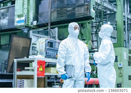 Male and female workers wearing protective clothing talking in a factory Male and female workers wearing protective clothing talking in a factory 136603071