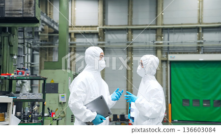 穿著防護衣的男女工人在工廠交談 136603084