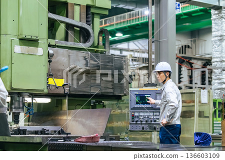 一名男工人在工廠的控制面板上操作機器 一名男工人在工廠的控制面板上操作機器 136603109