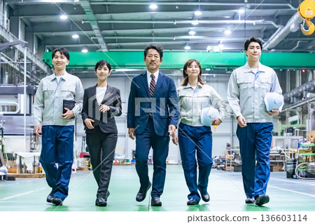 A group of workers walking through a factory A group of workers walking through a factory 136603114