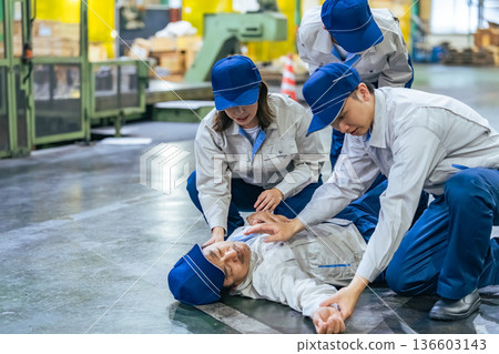 一群人為一名在工廠暈倒的工人提供醫療救助 一群人為一名在工廠暈倒的工人提供醫療救助 136603143