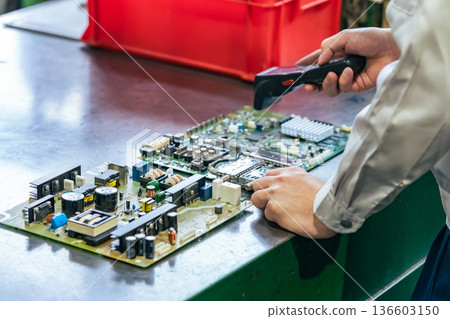 A worker inspects products using a handheld terminal at a factory 136603150