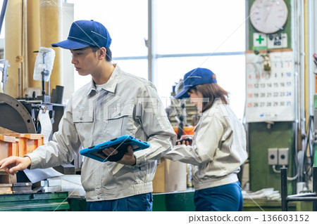 Group of workers holding a tablet working in a factory Group of workers holding a tablet working in a factory 136603152