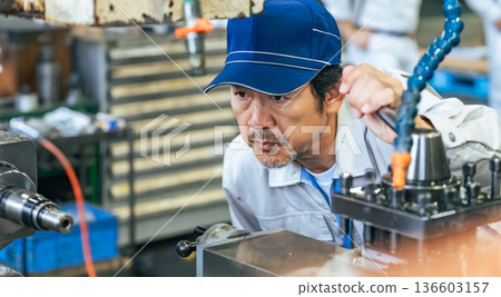 一名男工人在工廠操作機器 一名男工人在工廠操作機器 136603157