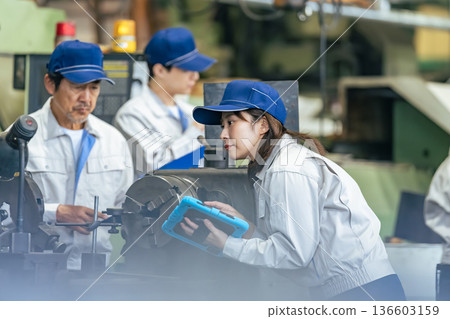 A group of workers inspecting a machine using a tablet PC 136603159