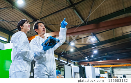 A female worker inspecting factory machinery with a tablet A female worker inspecting factory machinery with a tablet 136603182