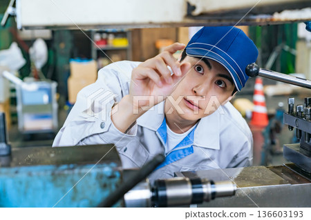 Male worker operating a machine in a factory Male worker operating a machine in a factory 136603193