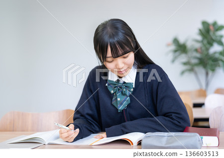 一名女高中生/考生正在書桌前認真學習。 一名女高中生/考生正在書桌前認真學習。 136603513