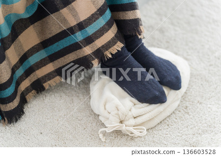 一位腳冷的女士正在使用熱水袋 一位腳冷的女士正在使用熱水袋 136603528