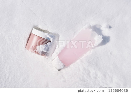 Pink cosmetics in snow for winter skincare routine 136604086