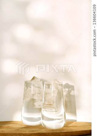 Drinking glasses with ice water and sunlight shadows Drinking glasses with ice water and sunlight shadows 136604109