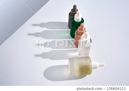 Cosmetic serum bottles creating shadows on white background Cosmetic serum bottles creating shadows on white background 136604111