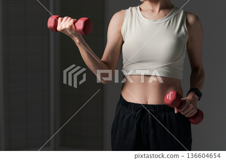 Part cut of a woman doing muscle training with dumbbells 136604654