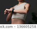 A woman in sportswear looking at a smartwatch 136605258