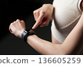 A woman in sportswear looking at a smartwatch 136605259