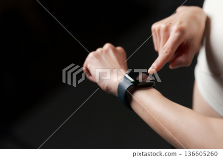 A woman in sportswear looking at a smartwatch 136605260