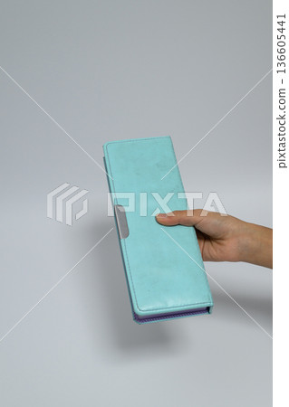 Child's hand holding a light blue pencil case and vertical space Child's hand holding a light blue pencil case and vertical space 136605441