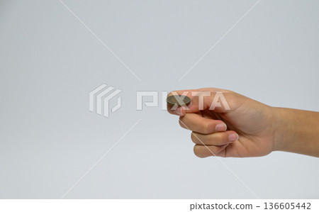 Child's hand holding a 10 yen coin in his fingertips Child's hand holding a 10 yen coin in his fingertips 136605442