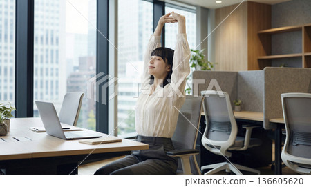 A Japanese woman stretching at her office desk to refresh herself 136605620