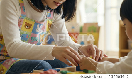 The hands of a nursery teacher playing with clay with children at a nursery school 136605642