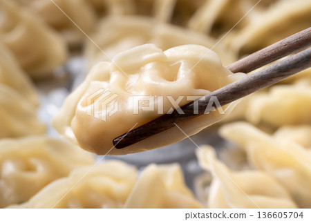 Close up of hot steamed dumpling being picked up by chopsticks in a steamer pot 136605704