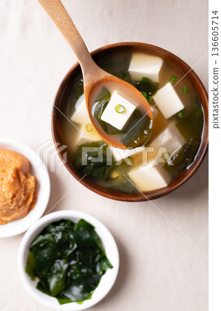 Healthy Japanese miso soup with soft tofu and seaweed in a wooden bowl being scooped with a spoon Healthy Japanese miso soup with soft tofu and seaweed in a wooden bowl being scooped with a spoon 136605714