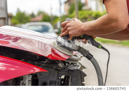 Repairing car body by puttying close up work after the accident by working sanding primer before painting. , The mechanic repair the car. Repairing car body by puttying close up work after the accident by working sanding primer before painting. , The mechanic repair the car. 136605745