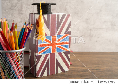 UK flag with graduate hat on english language book. UK flag with graduate hat on english language book. 136605769
