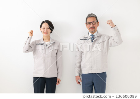 一個男人和一個女人穿著工作服做拳頭泵 一個男人和一個女人穿著工作服做拳頭泵 136606089