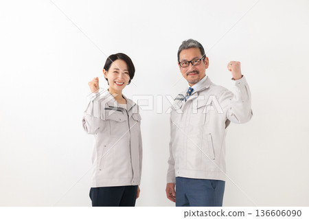 一個男人和一個女人穿著工作服做拳頭泵 一個男人和一個女人穿著工作服做拳頭泵 136606090