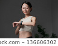 A woman doing muscle training looking at a smartwatch 136606302