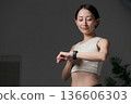 A woman doing muscle training looking at a smartwatch 136606303