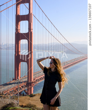 Stylish woman in black dress posing near Golden Gate Bridge 136607107